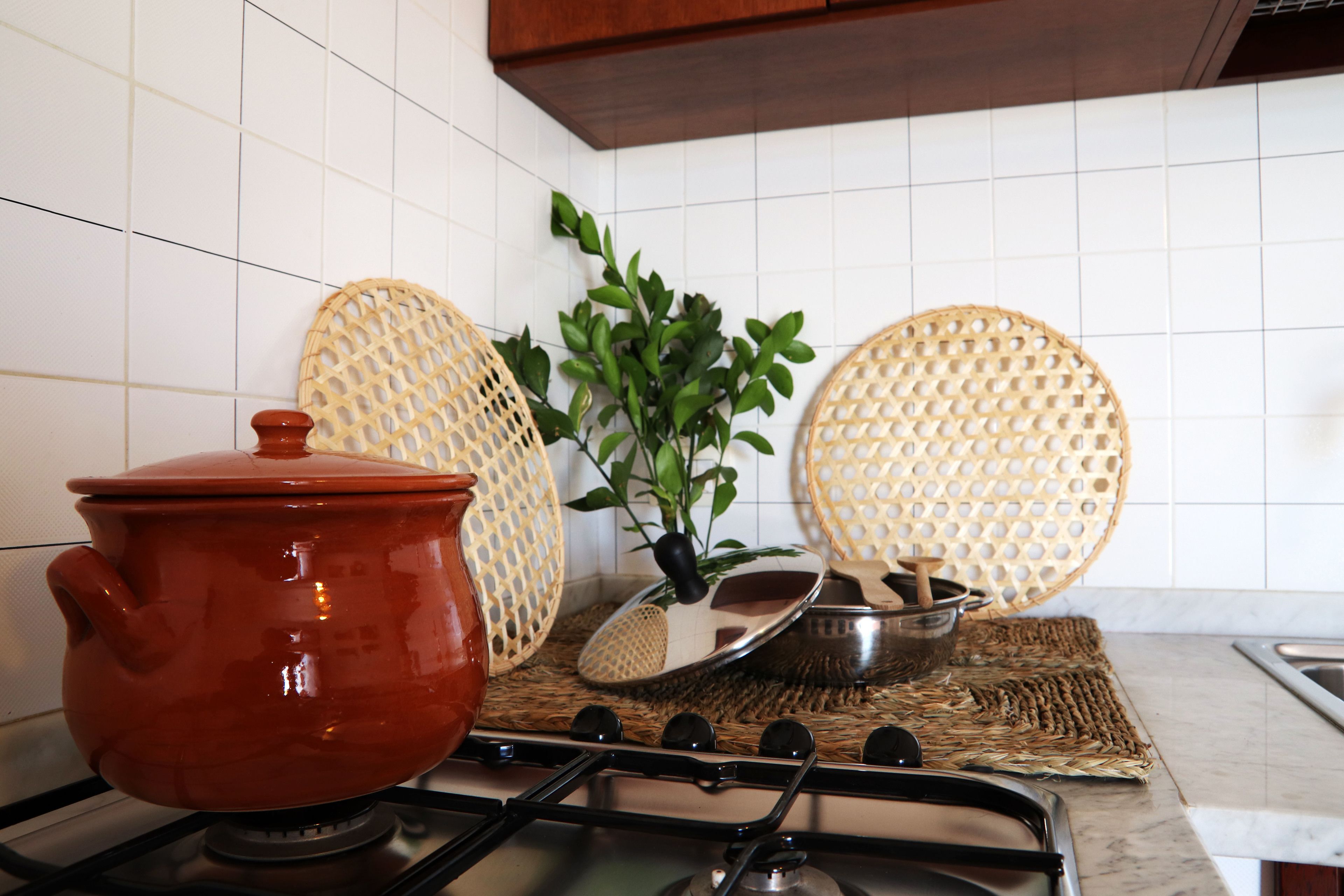A kitchen with a red pot on the stove, a woven placemat, and two woven baskets.