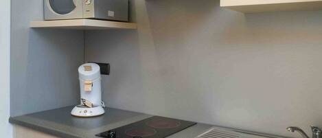 A modern kitchen with a built-in microwave, coffee maker, stainless steel sink, and a range hood.