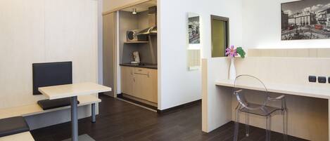 Una cocina moderna con microondas, cafetera y una pequeña mesa de comedor.
