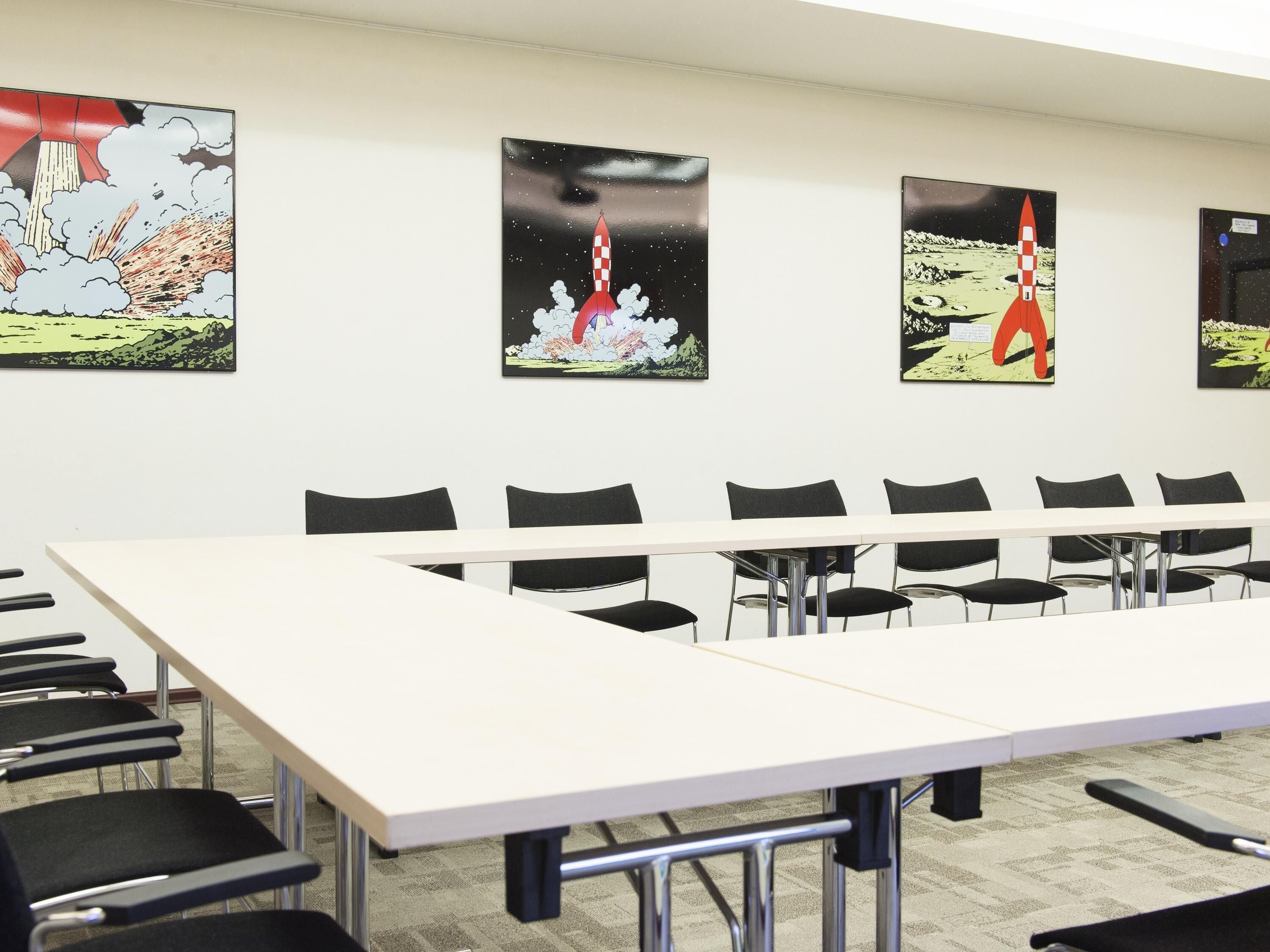 A conference room with a long table and chairs, and four rocket launch posters on the wall.