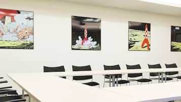 Une salle de conférence avec une longue table et des chaises, et quatre affiches représentant des lancements de fusées accrochées au mur.