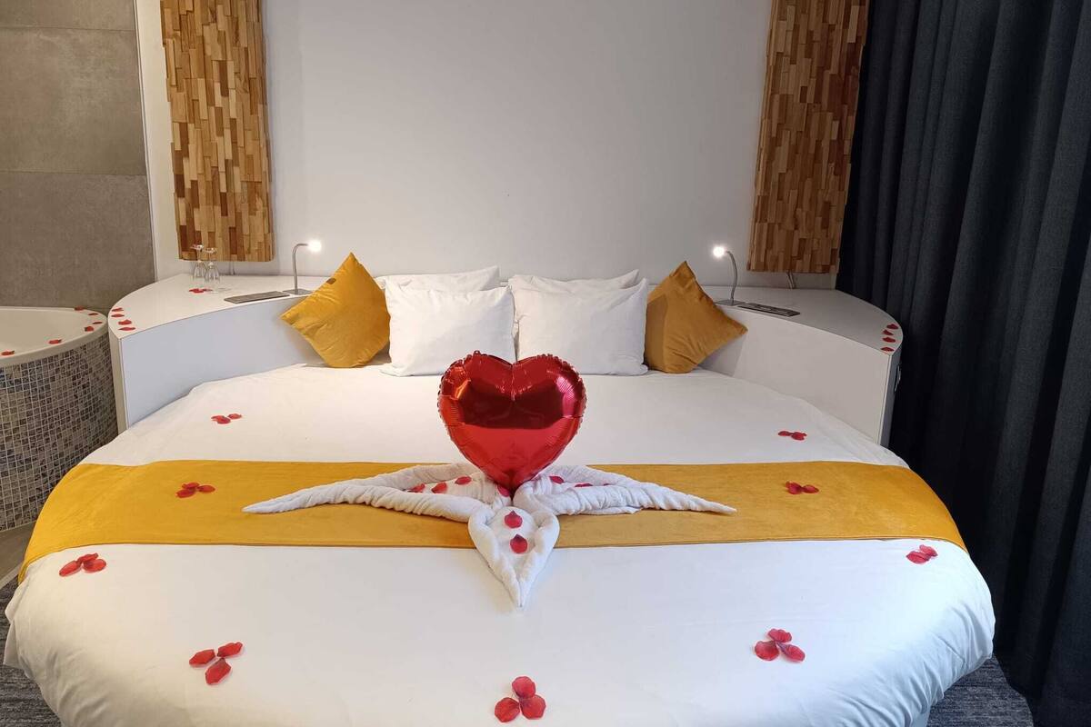 A hotel room with a bed, a bedside table, a mirror, and a wall with a wooden panel design.