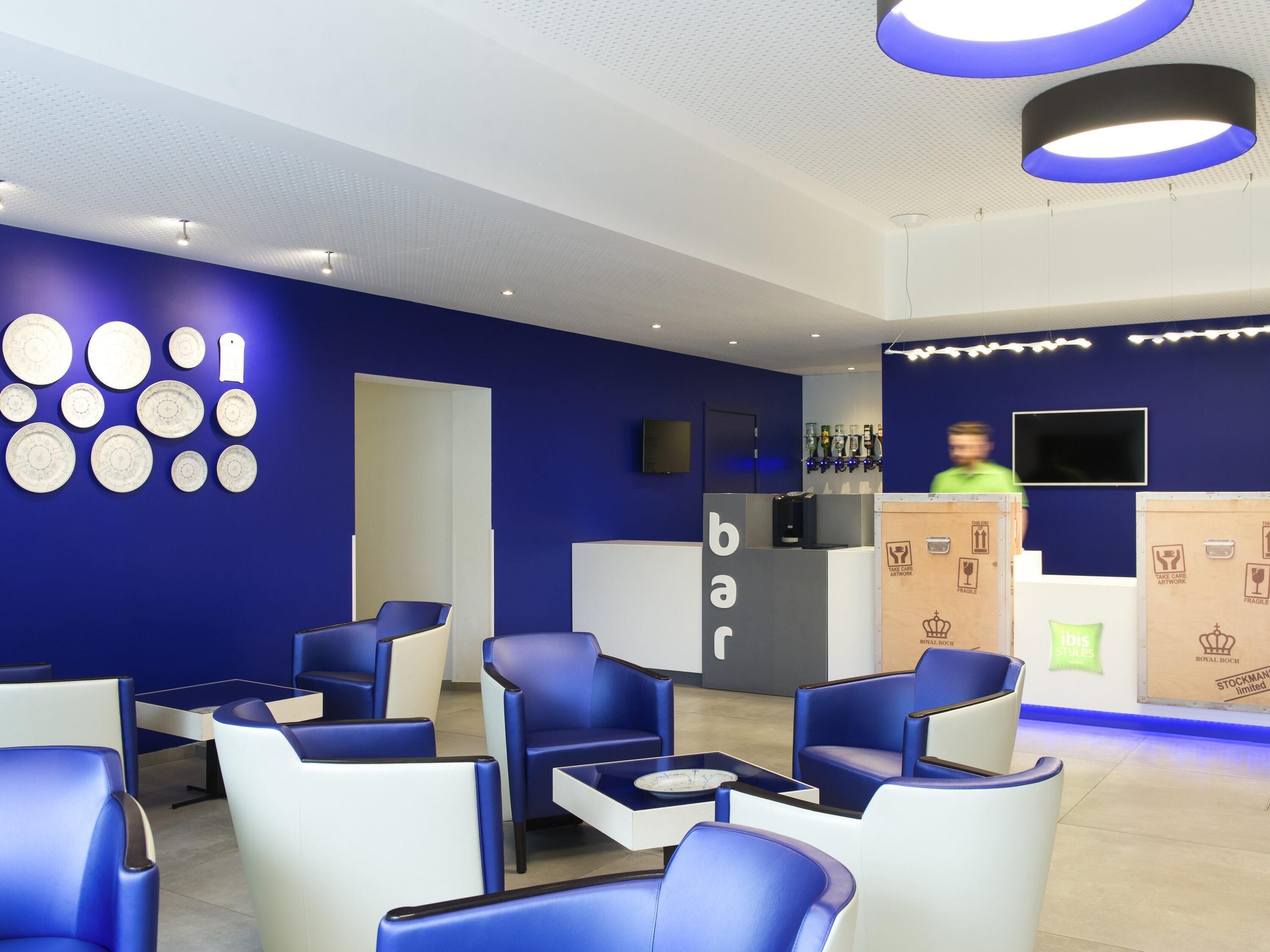Eine moderne Bar mit blauen Sitzgelegenheiten, einer Theke und einer Wand mit kreisförmigen Mustern.