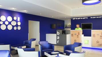 A modern bar area with blue seating, a counter, and a wall with circular patterns.