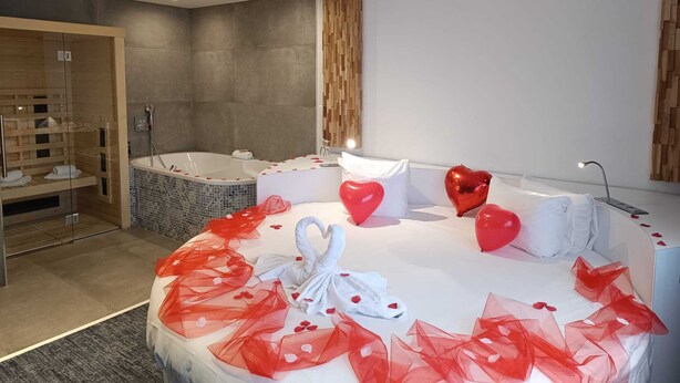 Une chambre d’hôtel moderne dotée d’un grand lit, d’une salle de bain séparée avec baignoire et d’un espace douche.