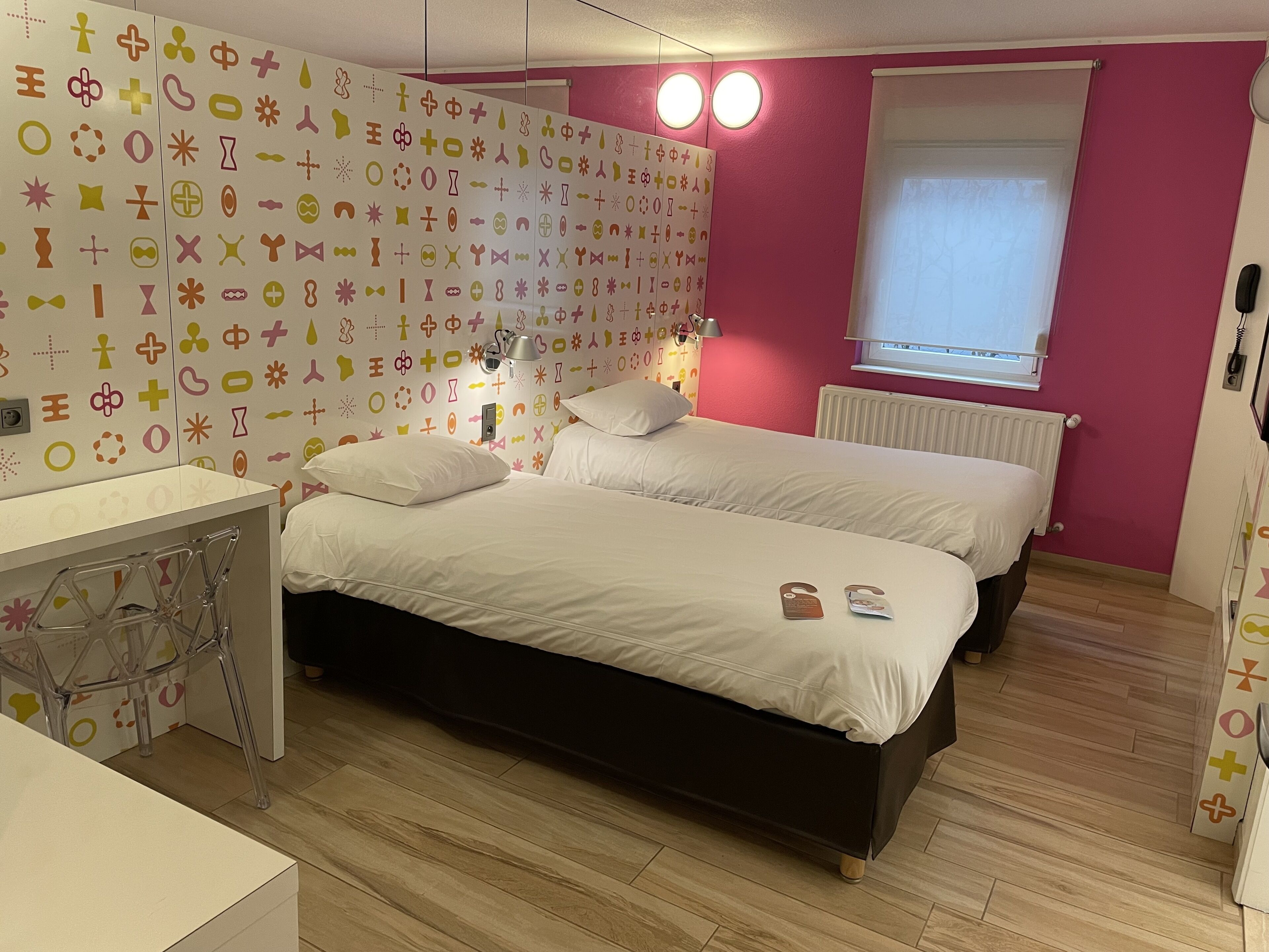 Une chambre à coucher avec un lit, une table de chevet et un mur orné de divers symboles.