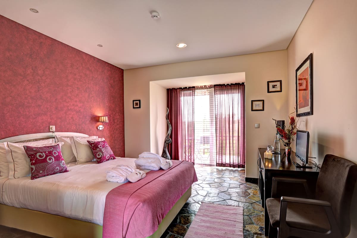 A hotel room with a bed, a desk with a computer, and a chair.