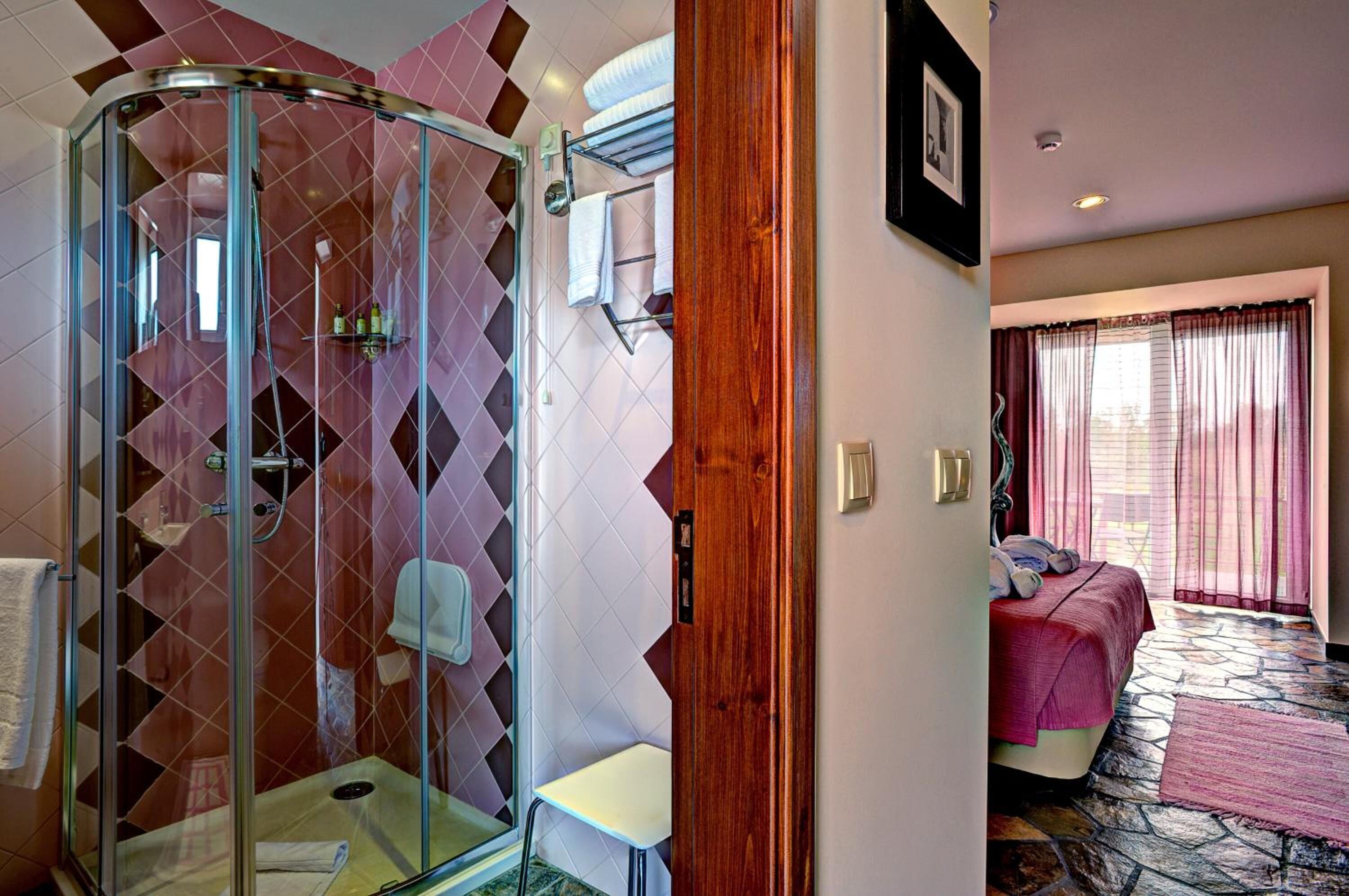 A bathroom with a glass-enclosed shower, a white sink, and a towel rack.