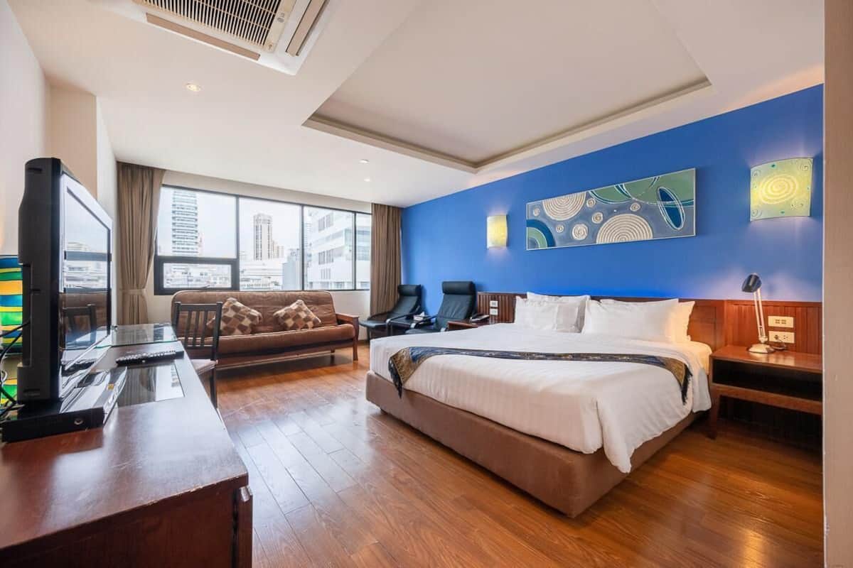 Ein Hotelzimmer mit einem großen Bett, einem Schreibtisch mit Computer, einer Sitzecke und einem Fernseher.