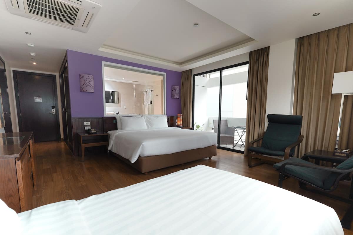 Ein Hotelzimmer mit einem großen Bett, einem Schreibtisch, einem Stuhl und einem Balkon mit Blick.