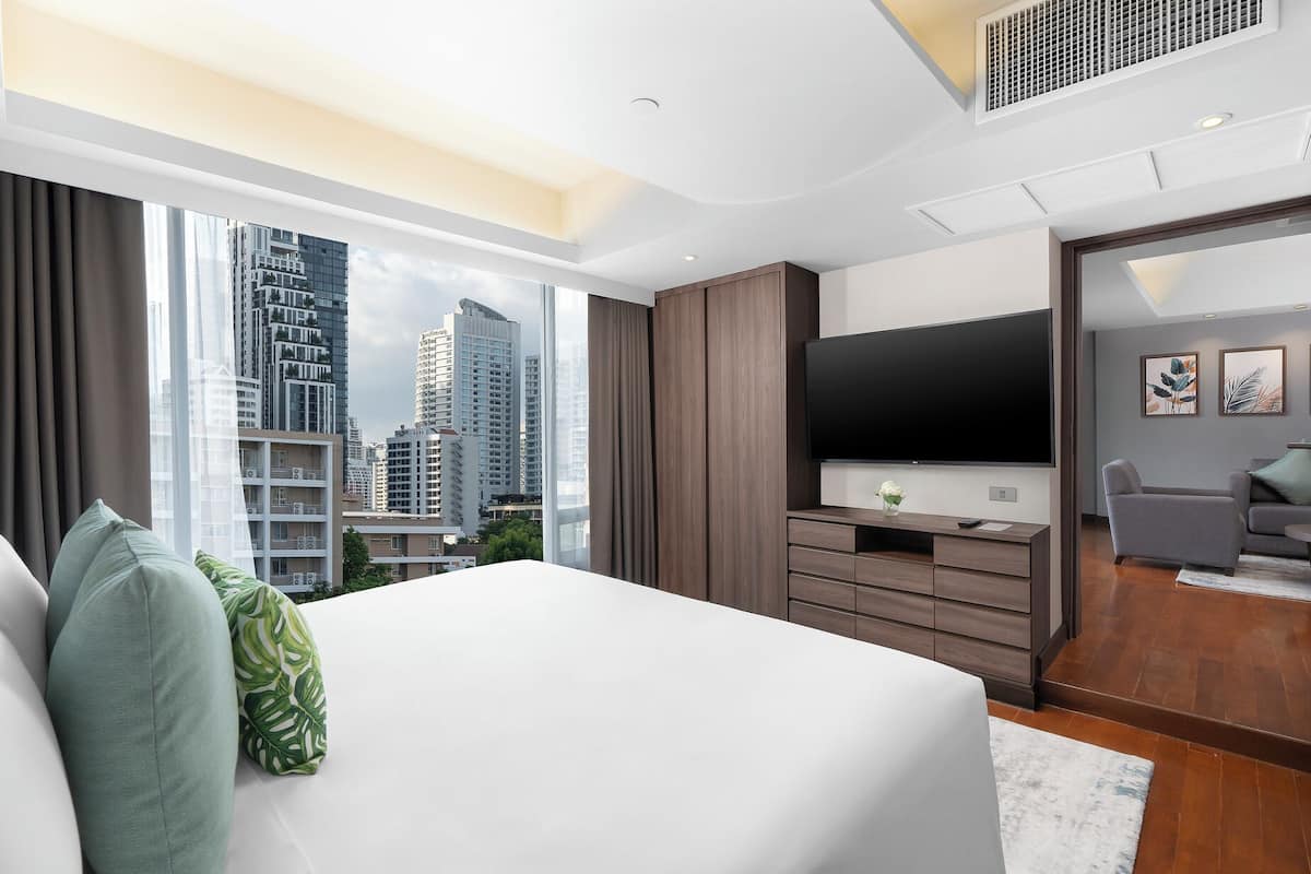 Ein modernes Hotelzimmer mit einem großen Bett, einem Flachbildfernseher und Blick auf die Stadt.