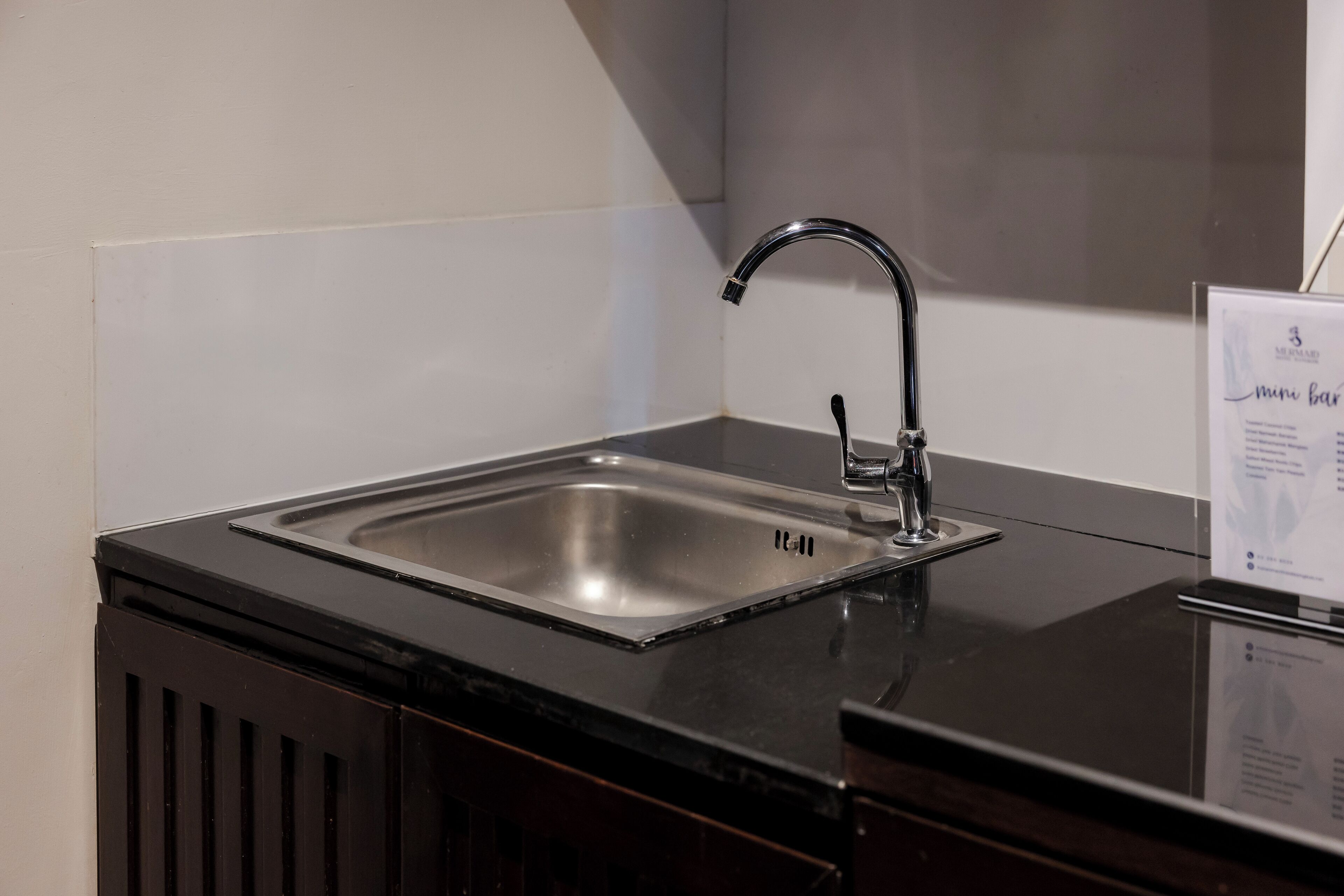 A modern kitchen with a stainless steel sink, black countertop, and a sleek faucet.