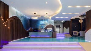 A modern hotel lobby with a reception desk, a pool area, and a seating area with chairs. - Hotel Mermaid Bangkok (Bangkok)