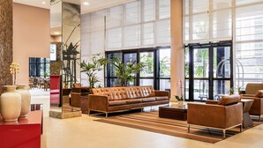 A spacious lobby with a large sofa, chairs, and potted plants. - Mercure Salvador Boulevard (Salvador)