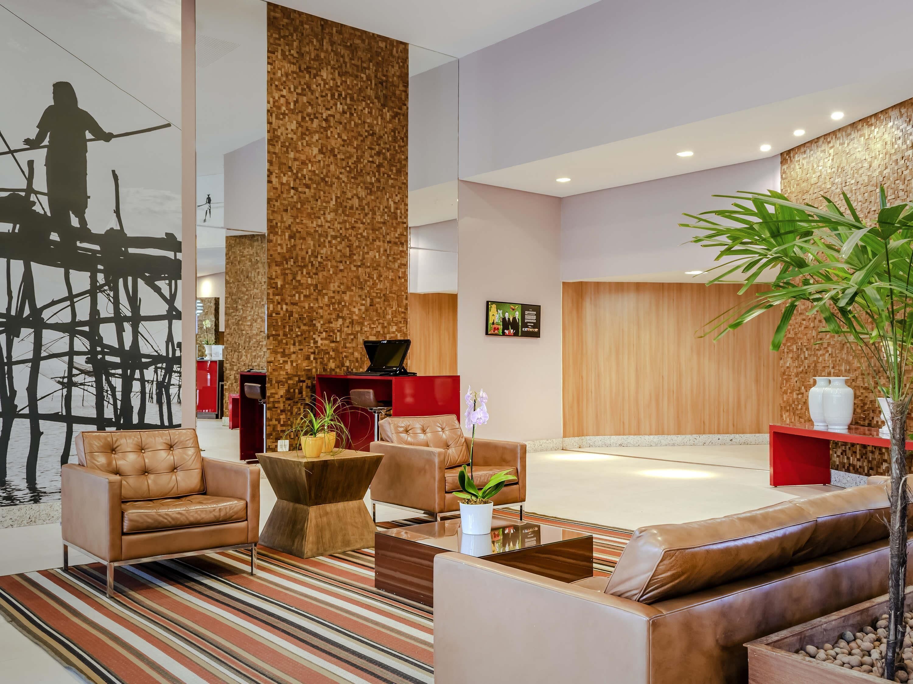 A modern lobby with leather sofas, a wooden accent wall, and a large black abstract painting.