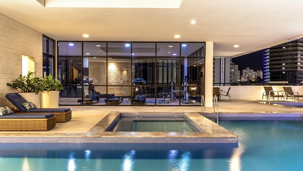 An indoor swimming pool with lounge chairs, a hot tub, and exercise equipment. - Mercure Salvador Boulevard (Salvador)