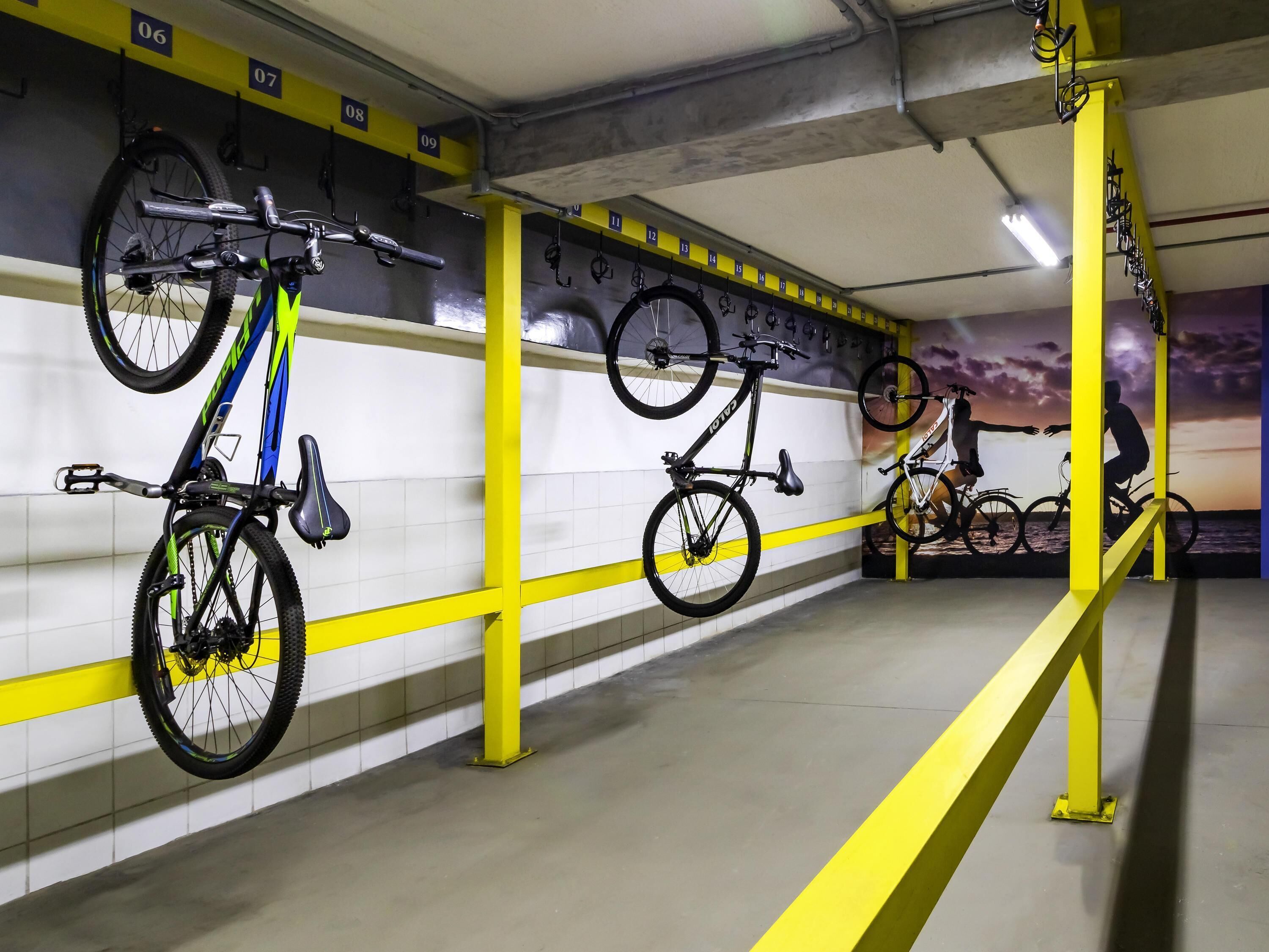 Een fietsenstallingsplaats met meerdere fietsen vastgezet in rekken, genummerd van 06 tot 15.