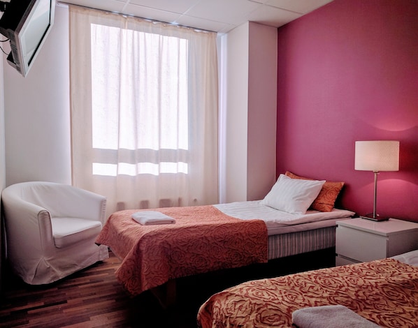A hotel room with two beds, a chair, a bedside table, and a lamp. - Center Hotel (Tallinn)