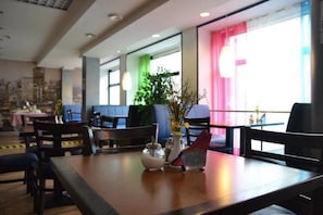 A hotel dining area with tables, chairs, and a vase with flowers. - Center Hotel (Tallinn)