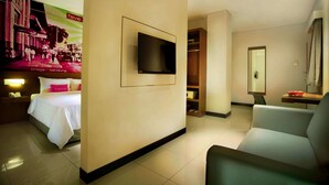 A hotel room with a bed, a TV mounted on the wall, a seating area, and a closet. - favehotel Braga (Bandung)