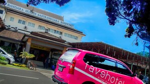 A pink shuttle bus with "favehotel" branding parked in front of a building with a sign reading "Bandara Husin Sastra Negara Bandung". - favehotel Braga (Bandung)
