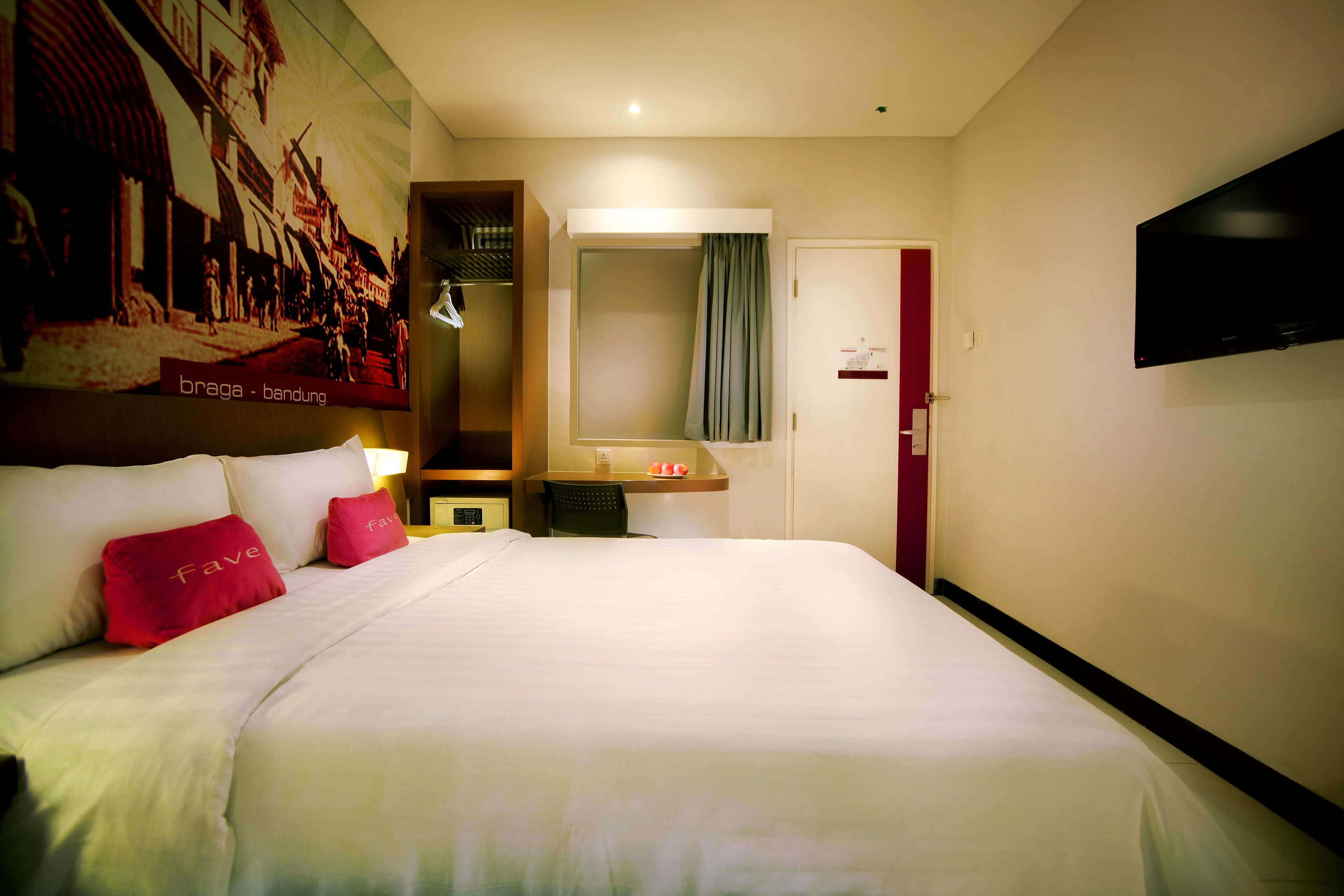 A hotel room with a large bed, a wardrobe, a mirror, a television, and a wall with a historical photo.