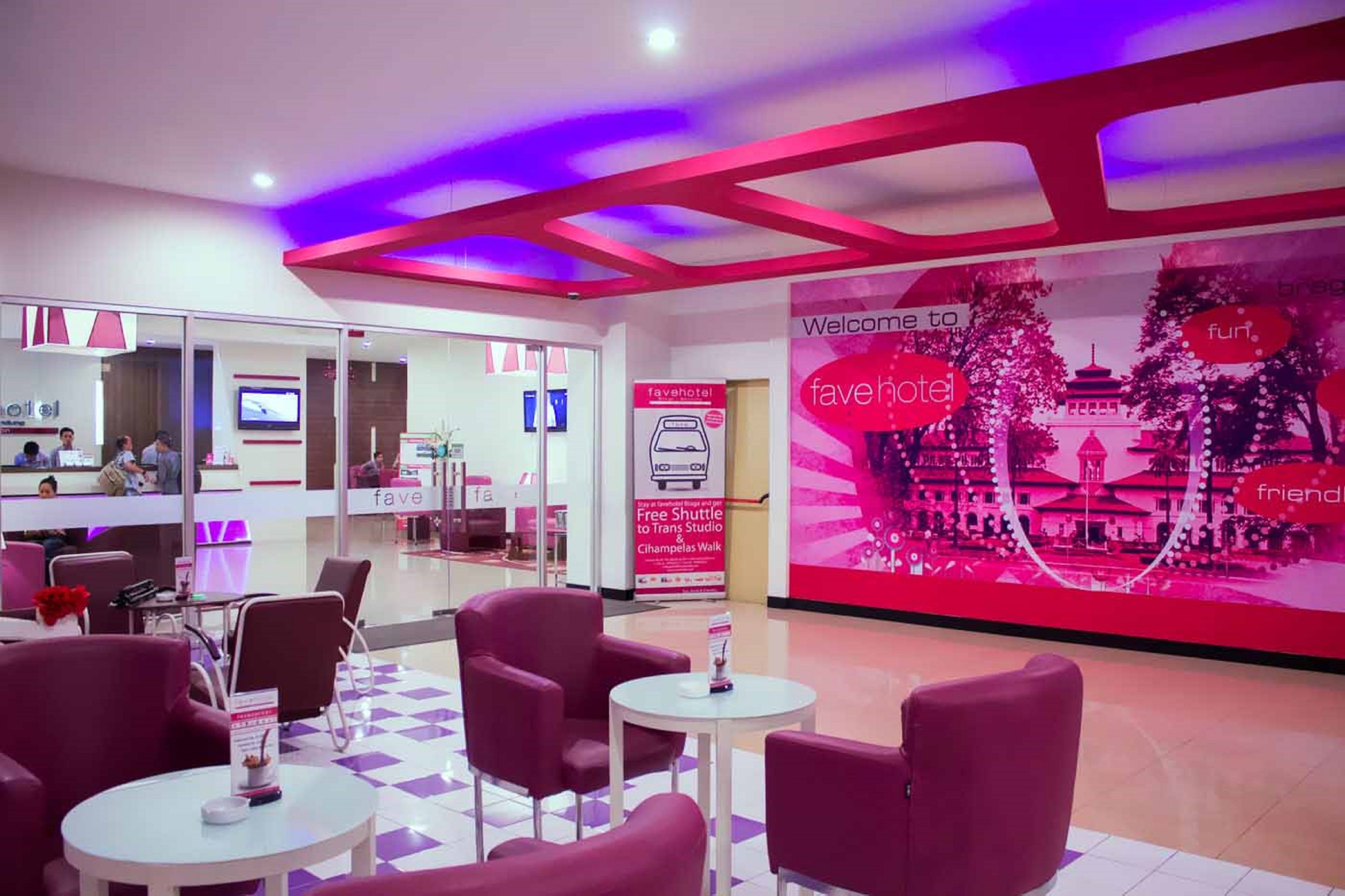 A hotel lobby with red and white decor, a reception desk, and a large digital display advertising the hotel.
