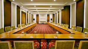 A conference room with a long table, chairs, and a presentation screen. - favehotel Braga (Bandung)