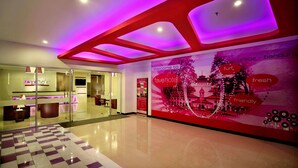 A hotel reception area with a modern design, including a checkered floor, glass doors, and a large welcome poster. - favehotel Braga (Bandung)