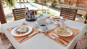 Ein Frühstückstisch ist gedeckt mit Speisen, Kaffeetassen und einem Teekessel.
