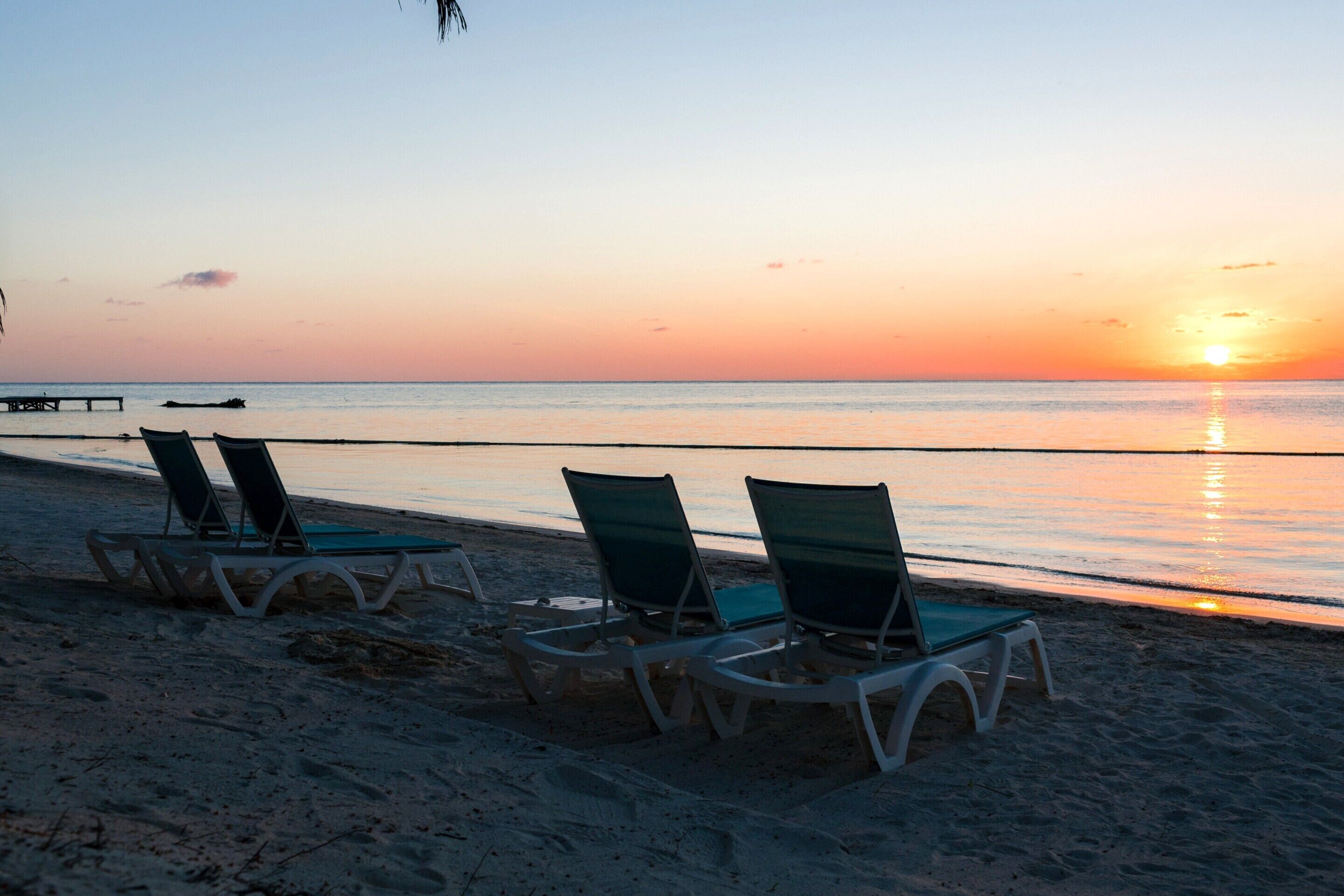 Une plage avec des chaises longues et une jetée en bois.