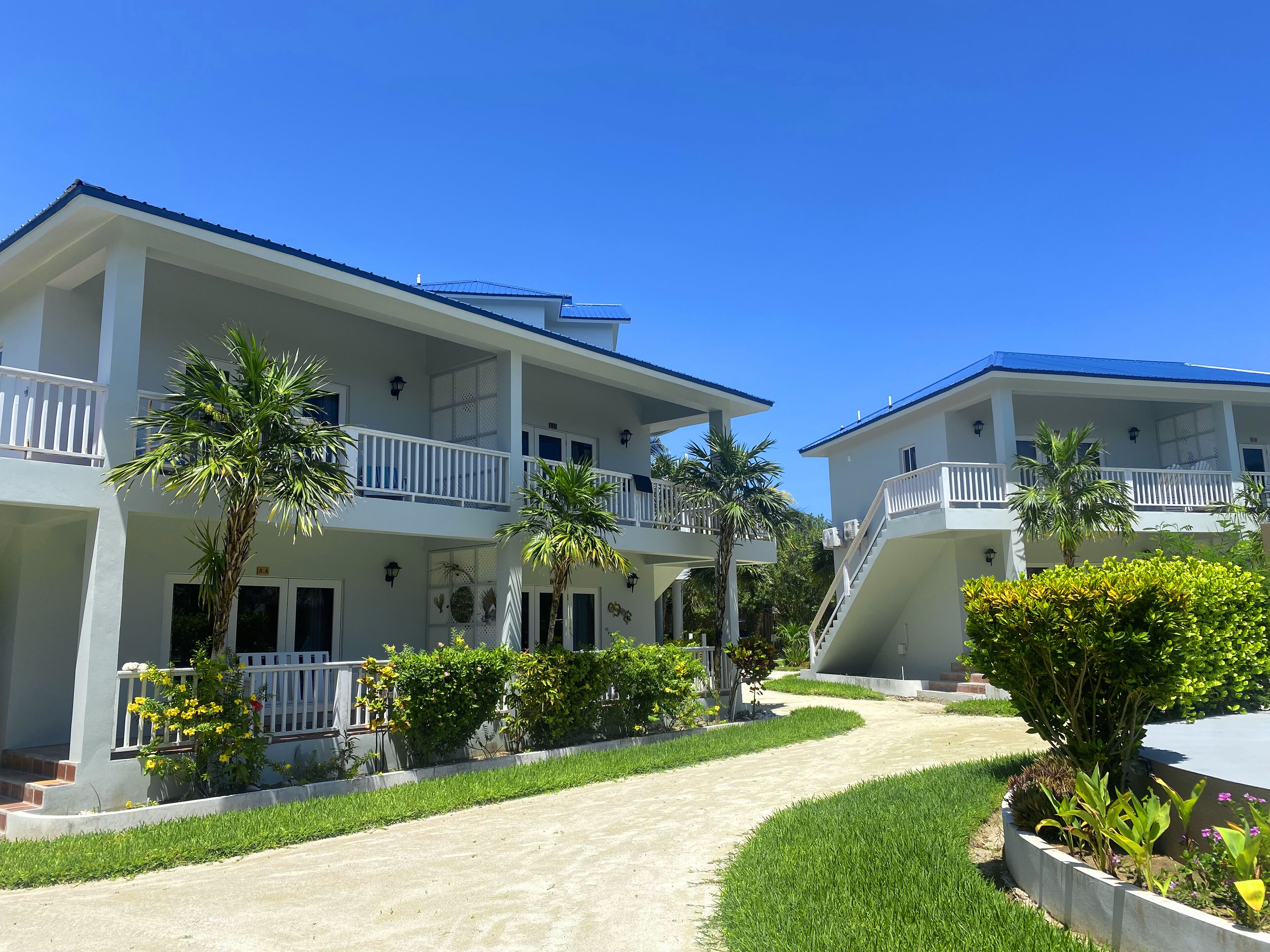 A two-story hotel with balconies, a central pathway, and surrounding greenery.