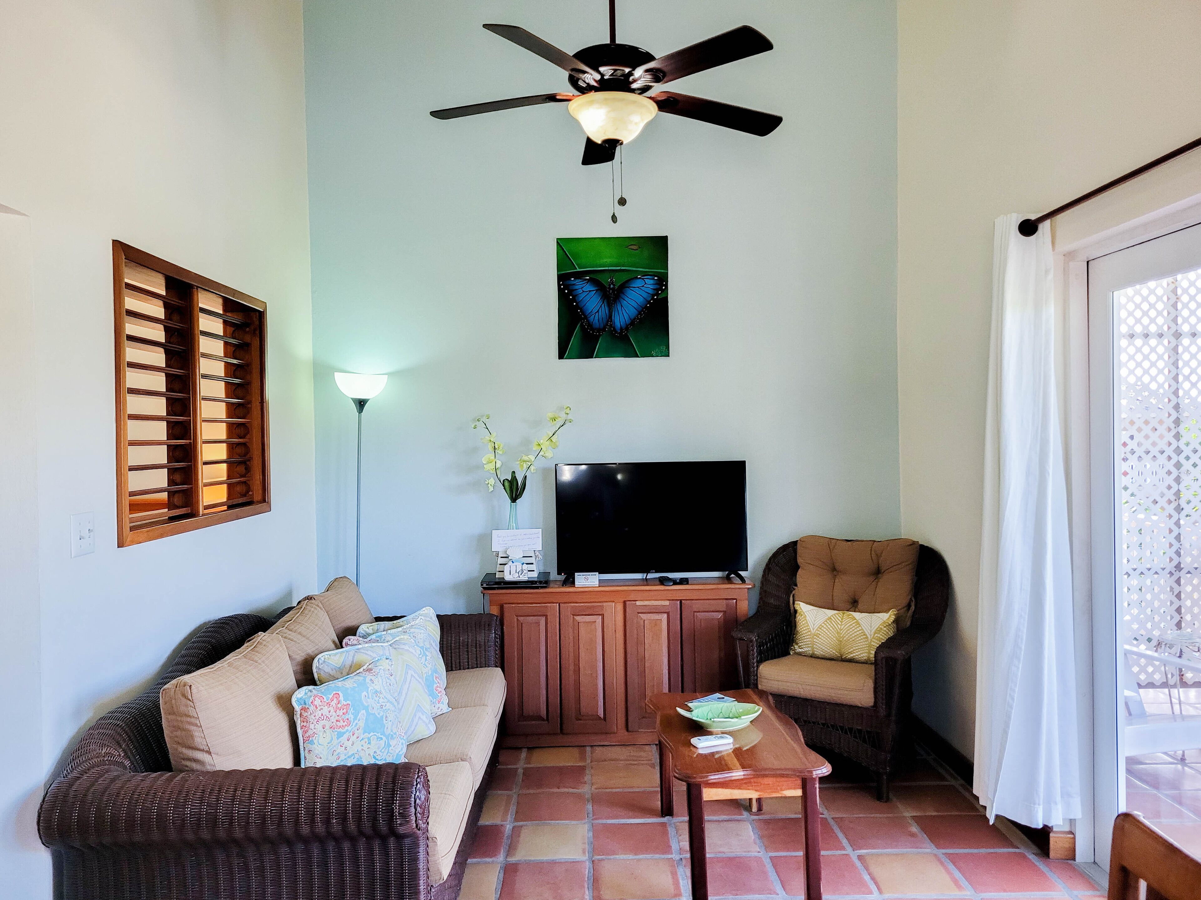 Una sala de estar con sofá, sillón, televisor y objetos decorativos.