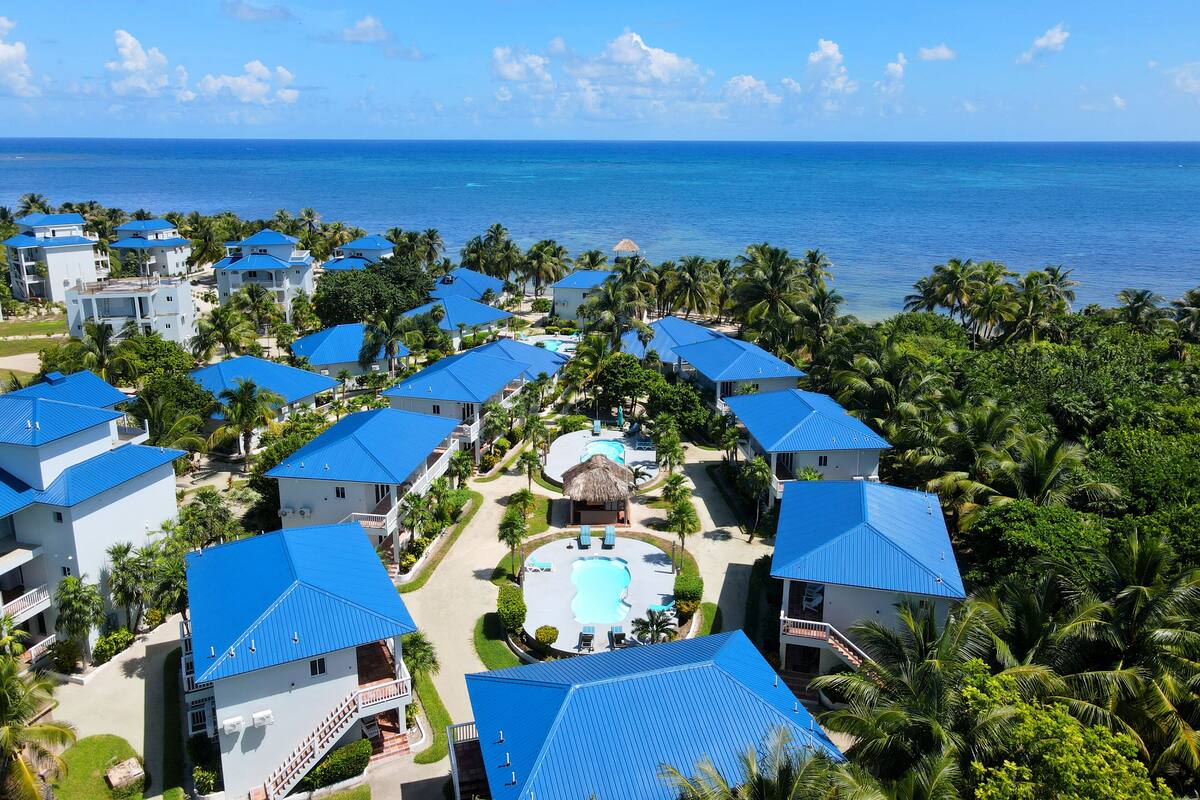 Un resort con varias edificaciones, una piscina y vista al océano.