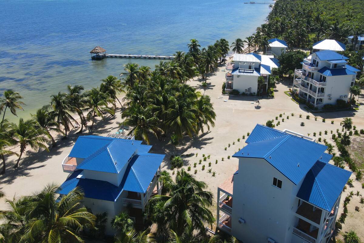 Un resort con varias edificaciones, una playa y un muelle.