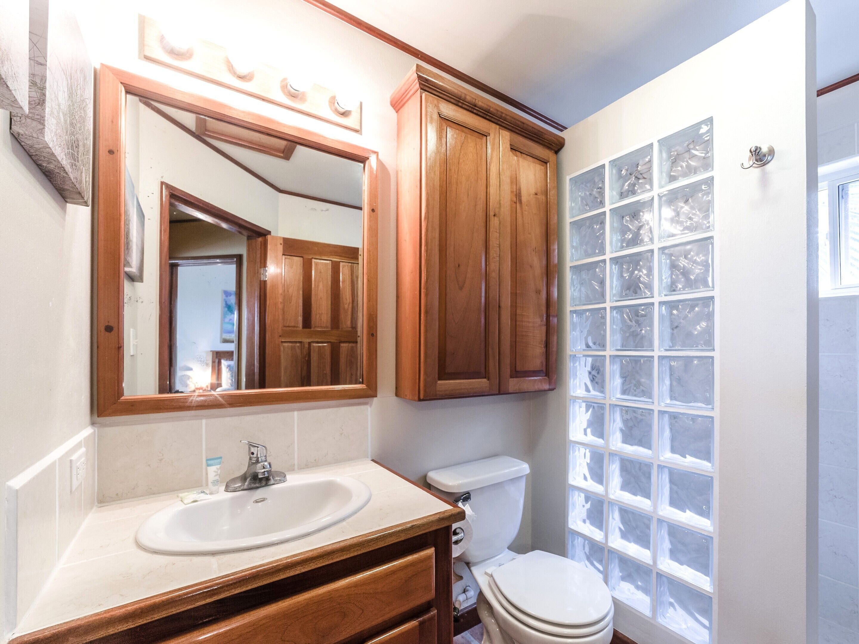 Une salle de bain avec un meuble-lavabo en bois, un évier, des toilettes et une fenêtre en verre dépoli.