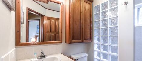 Une salle de bain avec un meuble-lavabo en bois, un évier, des toilettes et une fenêtre en verre dépoli.