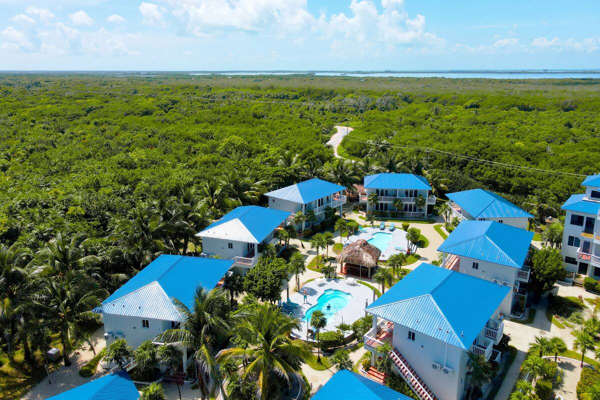 Un resort con varias construcciones, una piscina y abundante vegetación.