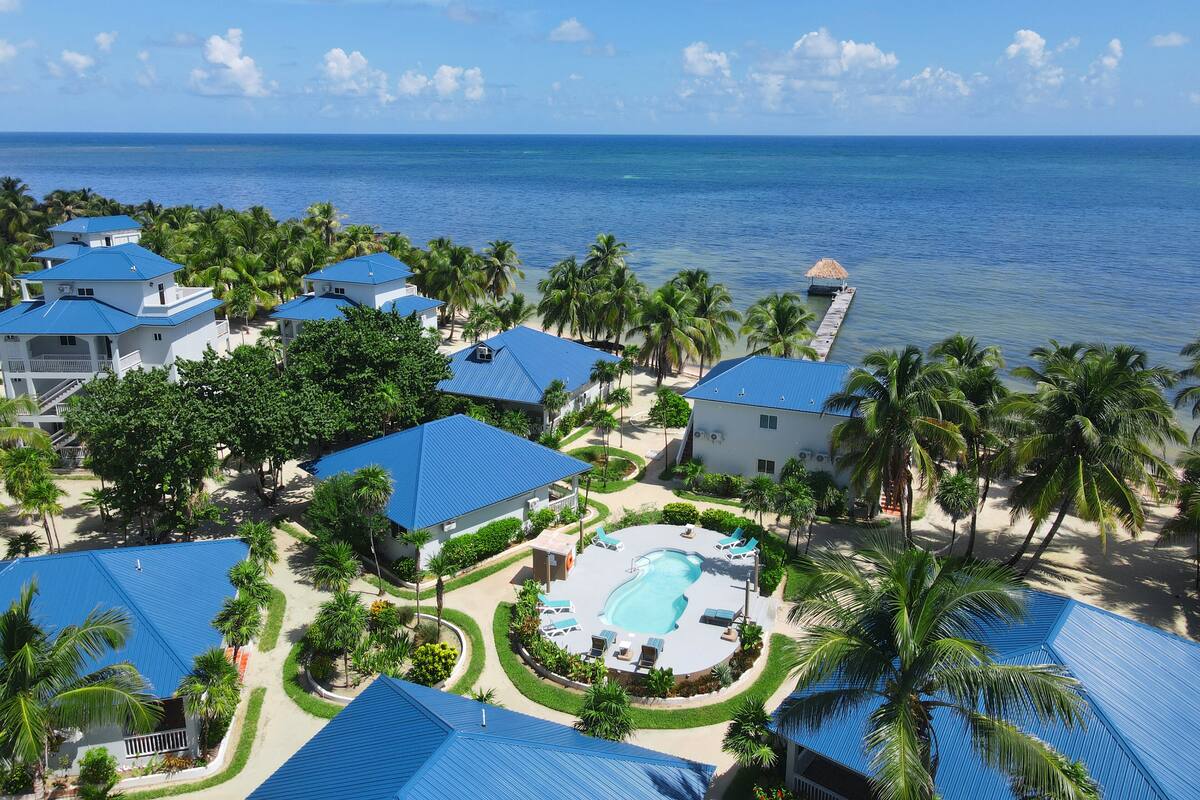 Un resort con varias construcciones, una piscina y vista al océano.