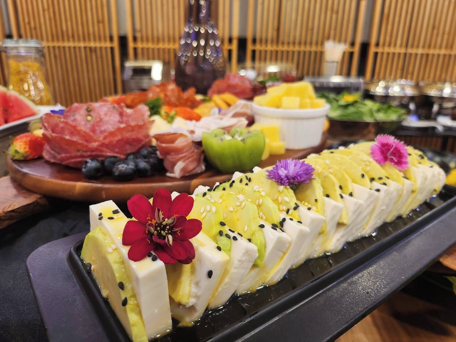 A buffet with various food items including meats, cheeses, and fruits.