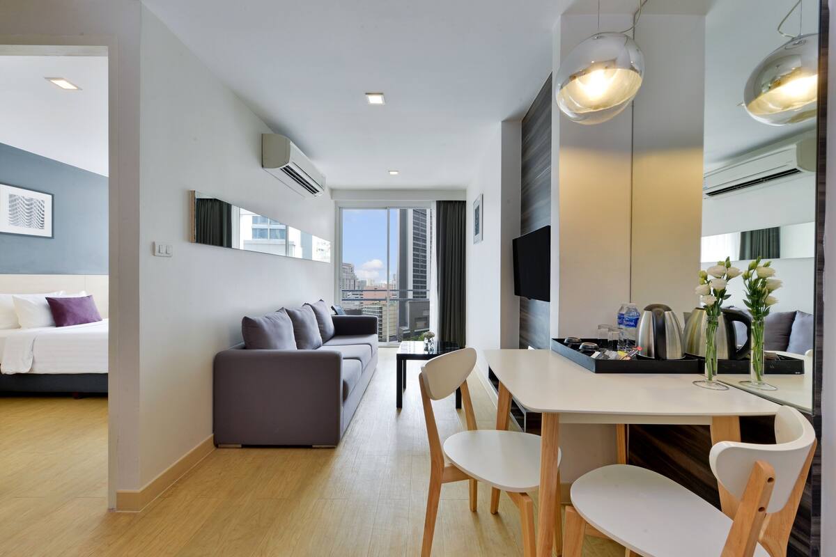 A modern living room with a sofa, dining table, chairs, and a TV.