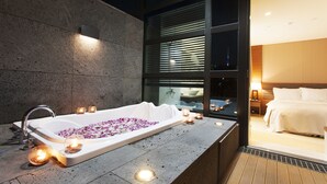 Un baño moderno con una bañera independiente, velas y vista a la ciudad de noche.