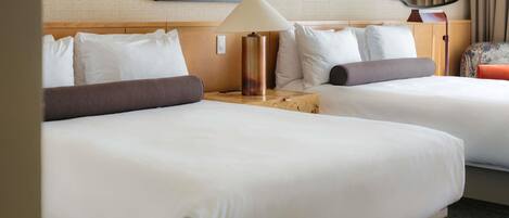 Ett hotellrum med två sängar, en lampa, en spegel och en tavla på väggen.