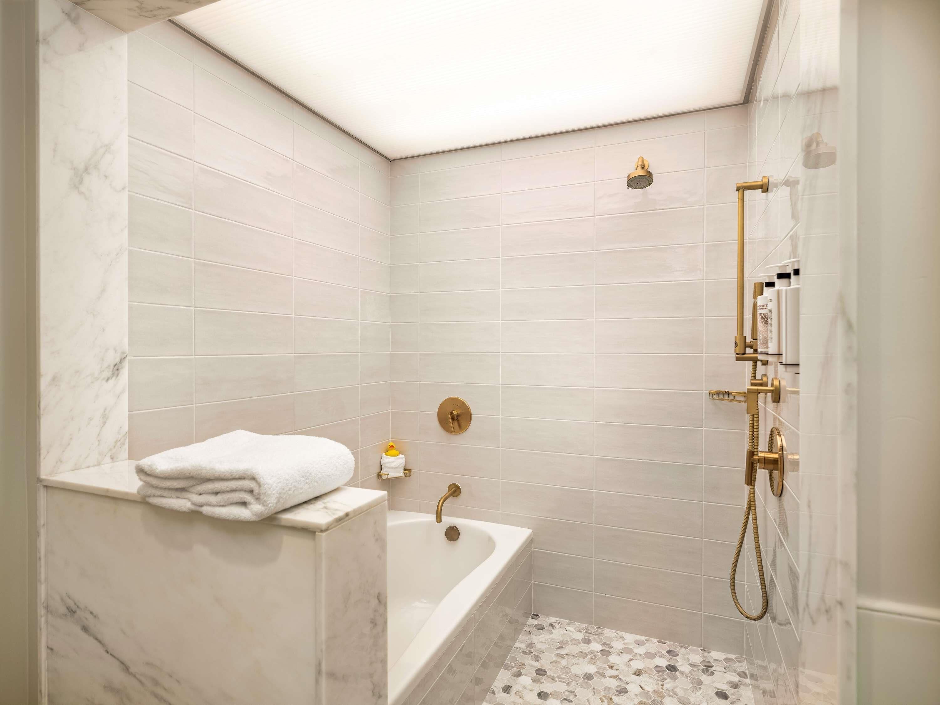 Une salle de bain équipée d’une baignoire, d’une douche avec un pommeau de douche amovible et d’un porte-serviettes.