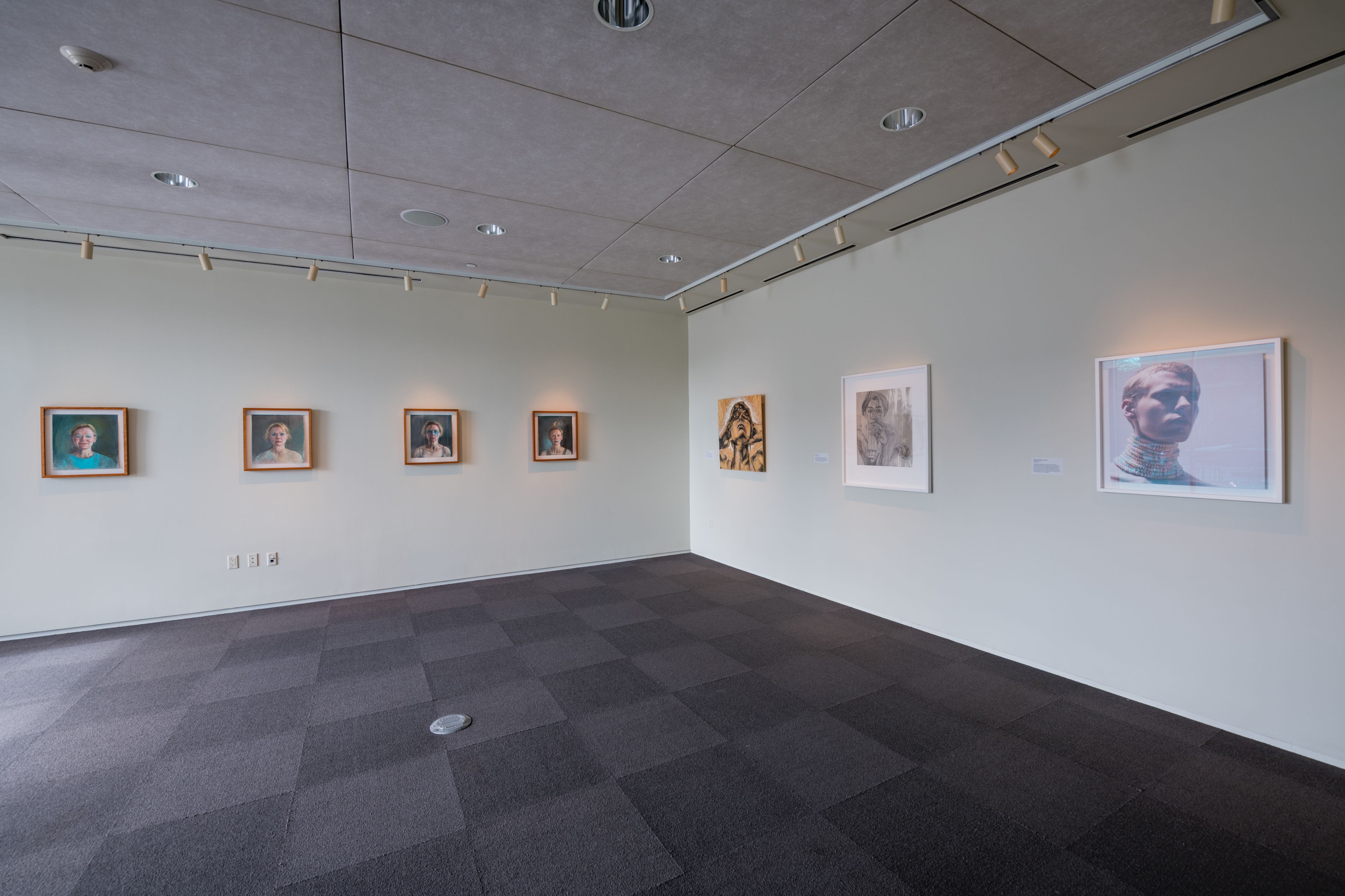 An art gallery with a clean, modern interior featuring a tiled floor and a series of framed artworks on the walls.