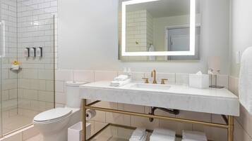 A modern bathroom with a white sink, gold fixtures, and a large mirror.
