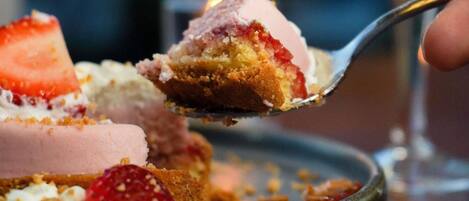 A dessert with strawberries and a spoonful being lifted.