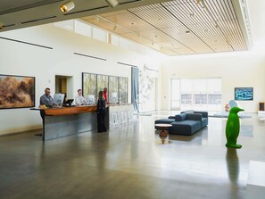 A spacious lobby with a reception desk, seating area, and large windows.