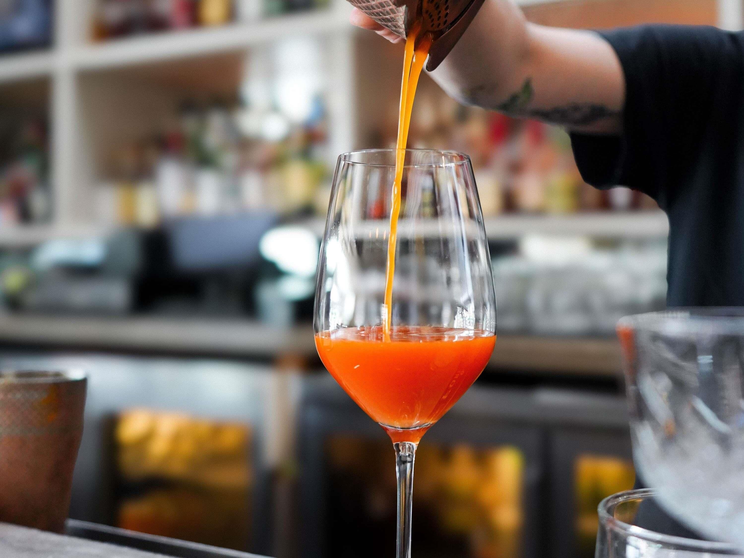 A bartender pouring a drink into a martini glass.
