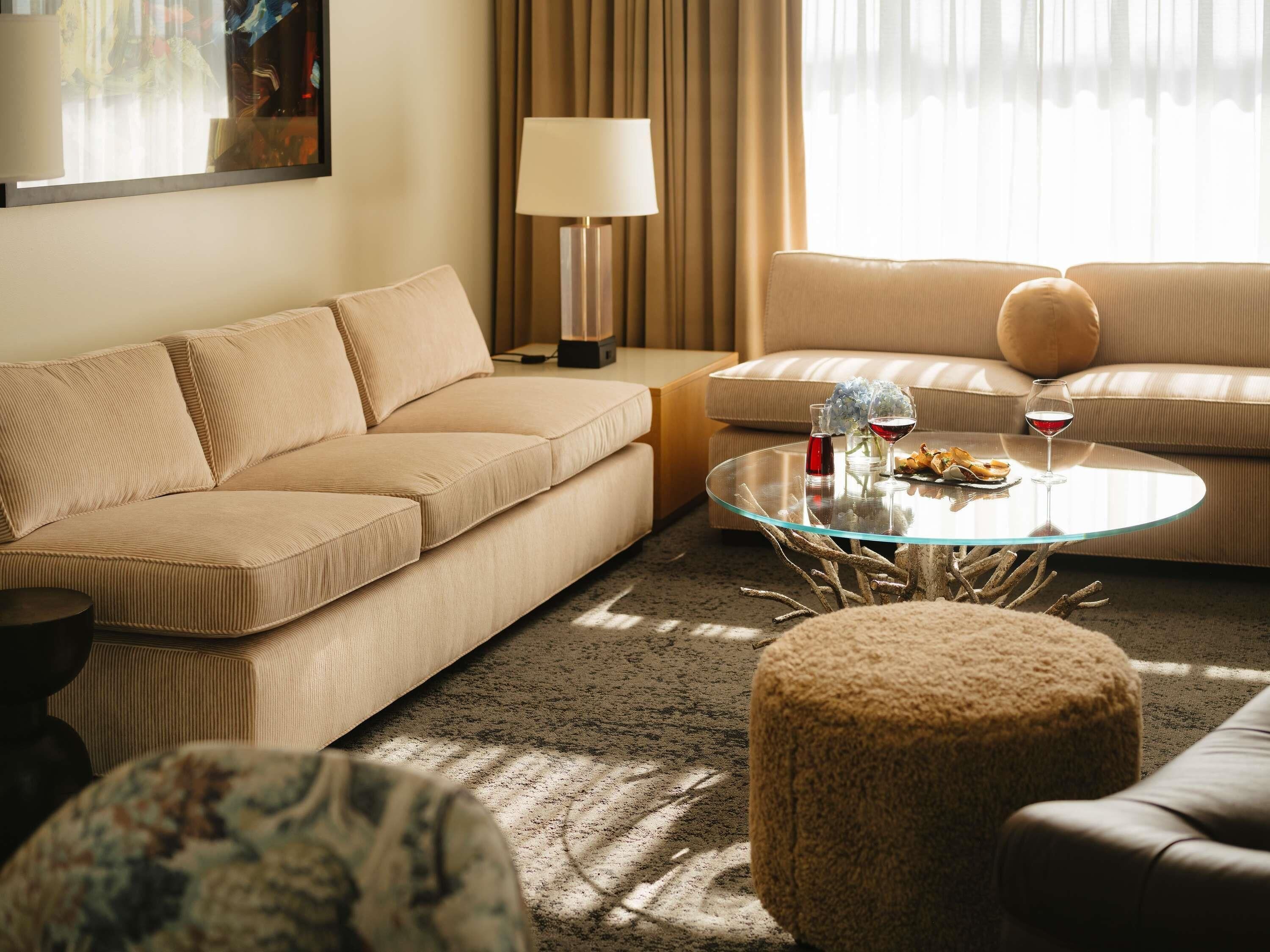 A modern living room with a beige sofa, a glass coffee table, and a lamp.